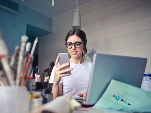 Girl at desk with phone and laptop